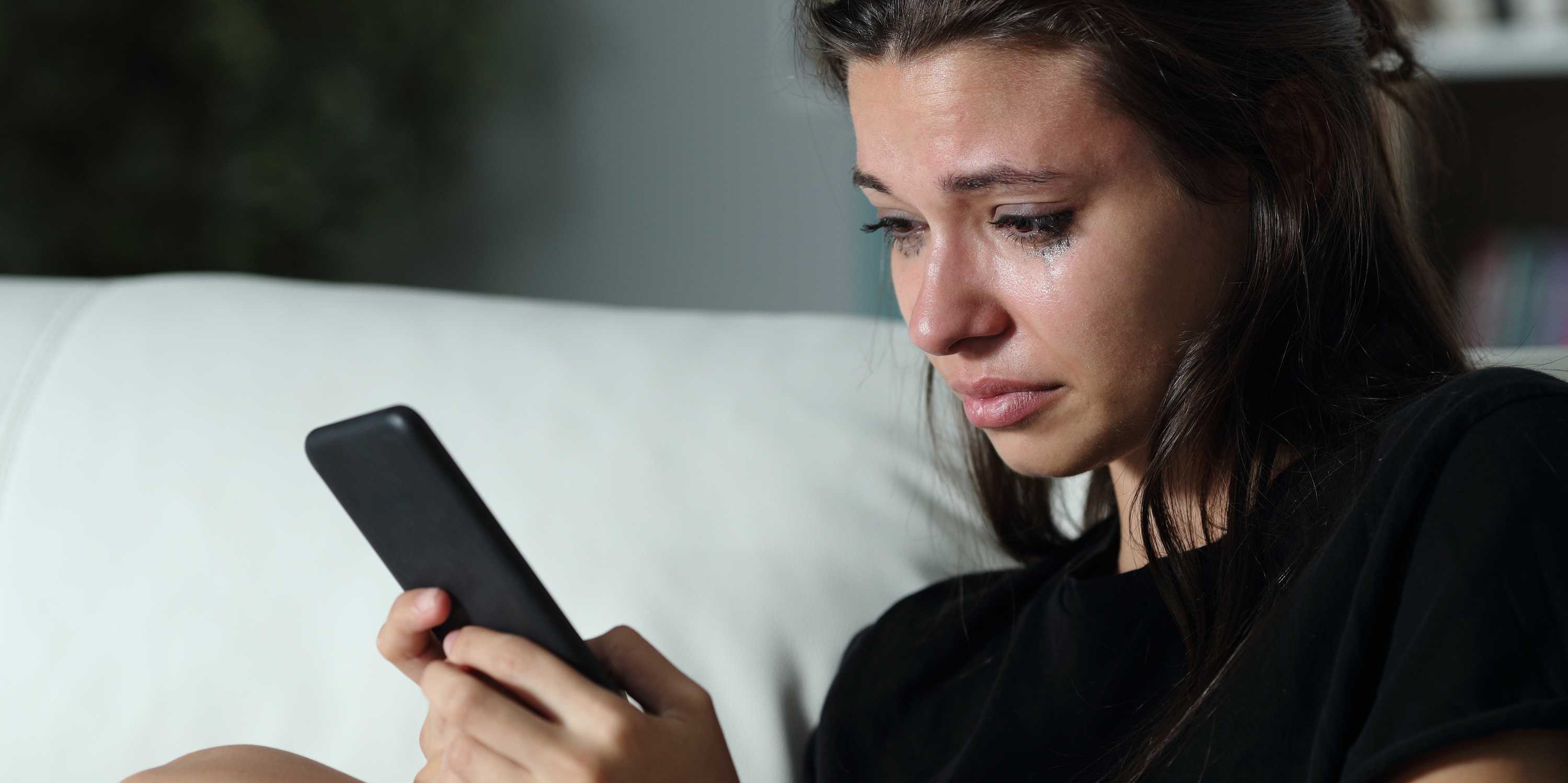teen girl reading cyberbully messages on phone